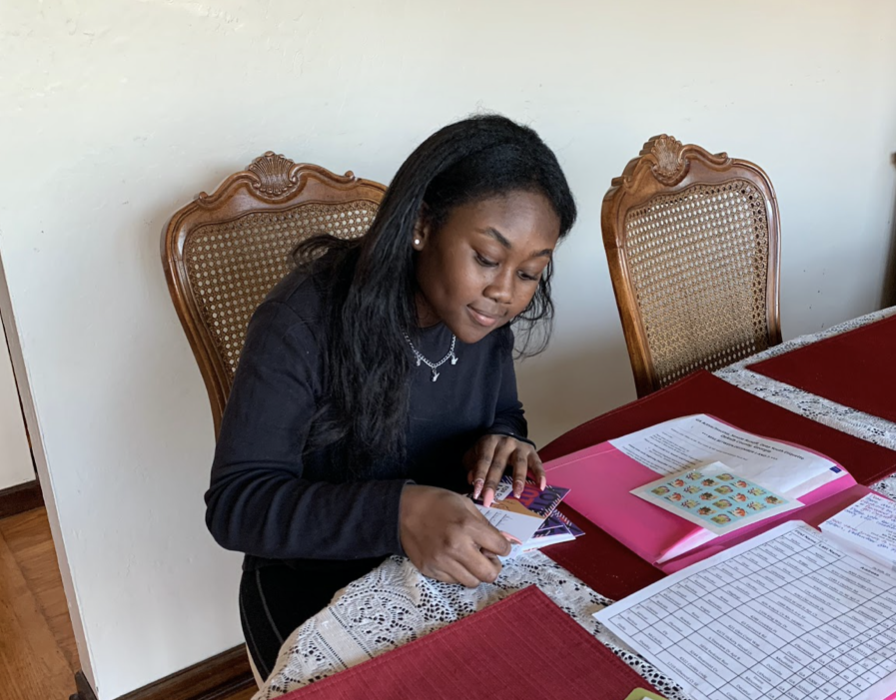 An African American woman puts stamps at the dining table.