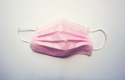 a pink surgical mask lays on a white background